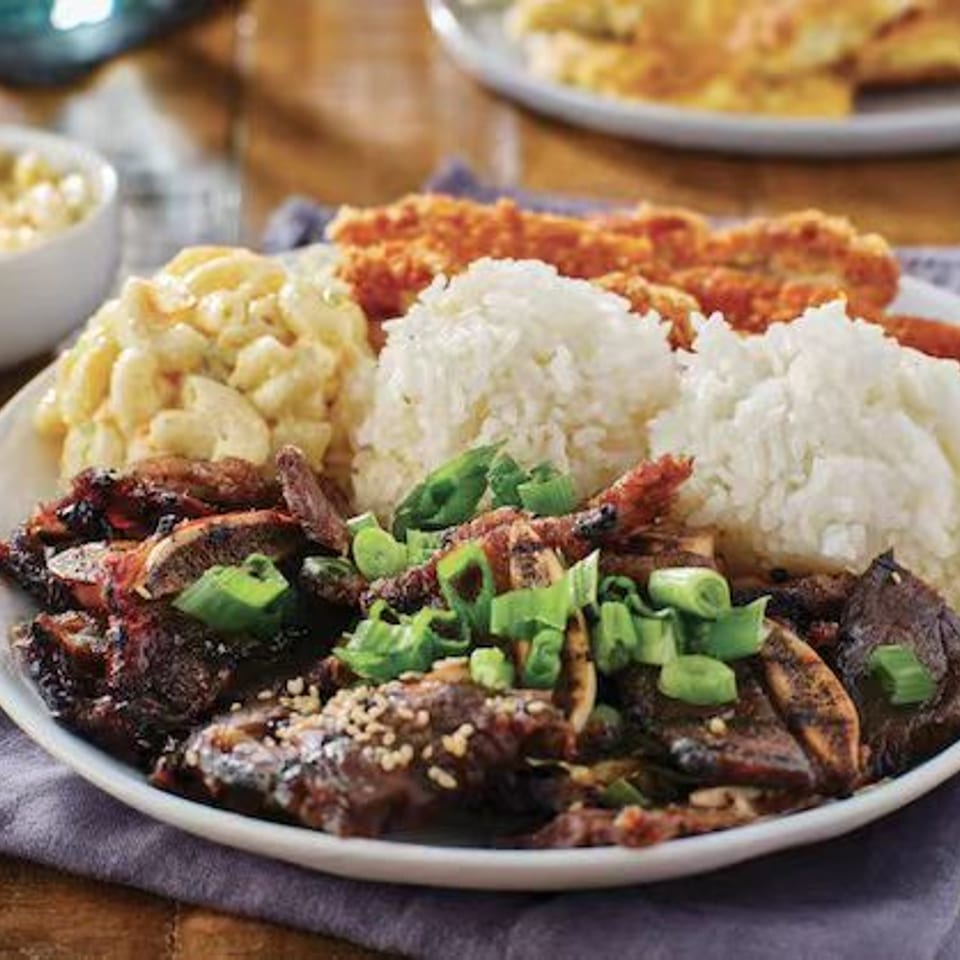Grilled ribs with green onions, rice, macaroni salad, and breaded chicken.