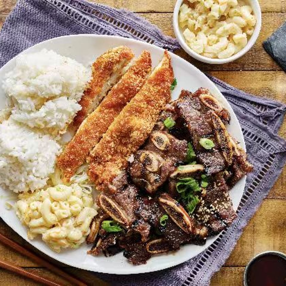 Grilled ribs and breaded chicken served with rice and macaroni salad.