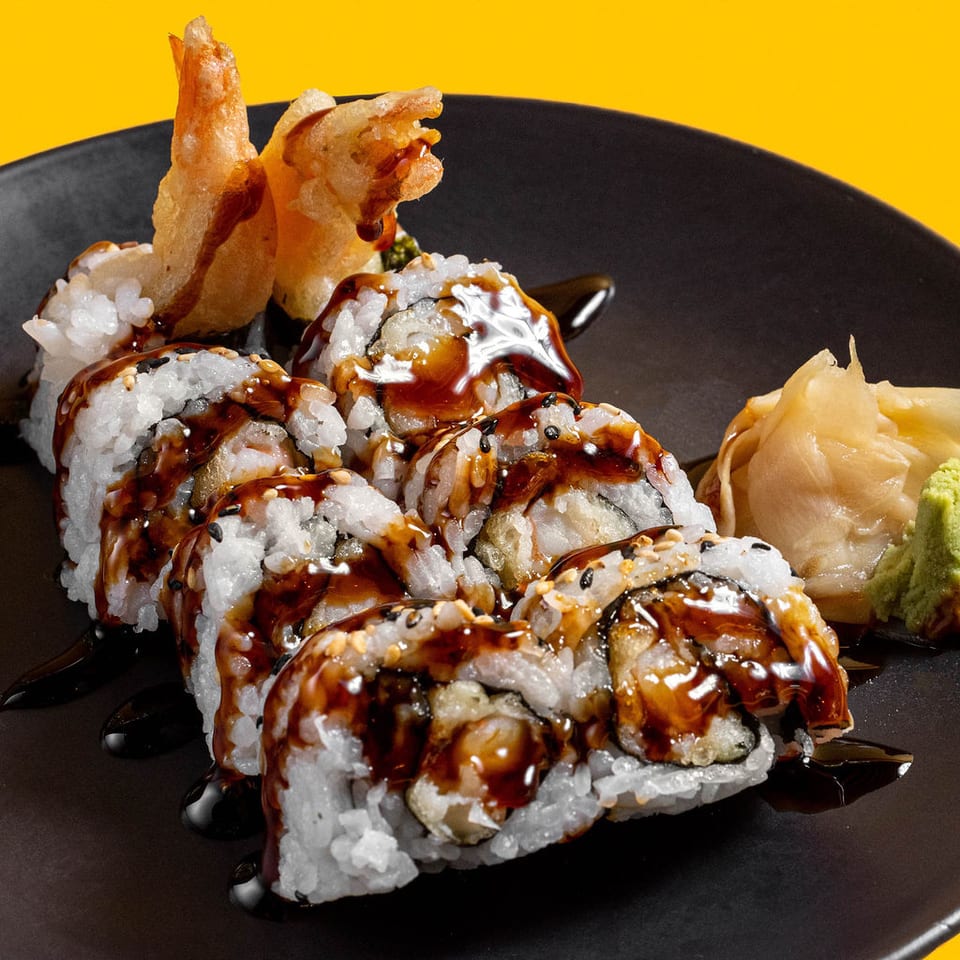 Shrimp tempura sushi rolls with sauce, ginger, and wasabi.